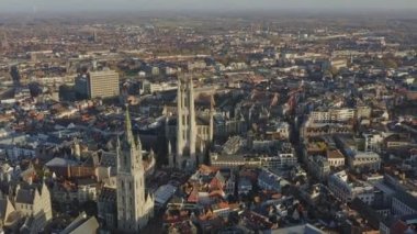 Gent Belçika Hava Aracı V11, günbatımında kilise şehir manzaralı şehir merkezi üzerinde uçuyor.