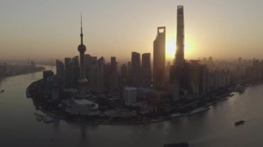 Shanghai China Aerial v75 Nehrin üzerinde ters yöne dönüyor. Pudong rıhtımına bakıyor. Bund da gündoğumunda ön cephede.