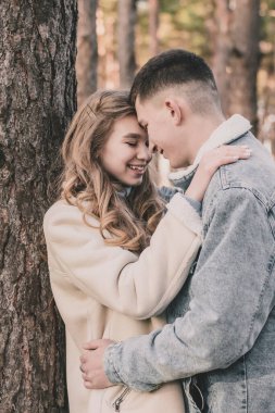 Adam kızı ağaca yasladı ve ona sarıldı. O da çam ormanındayken gülümsedi.