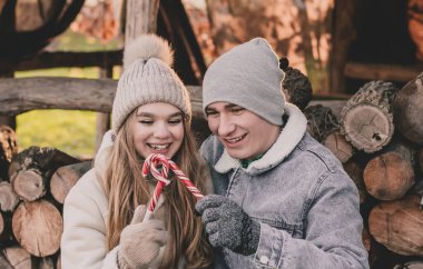 Yakacak odunların arkasında oturan ve ellerinde şeker tutan çift.
