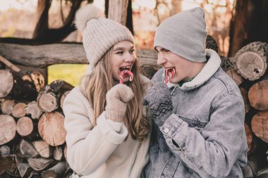 Yakacak odunların arkasında oturan, şeker yiyen ve birbirlerine gülümseyen bir çift.