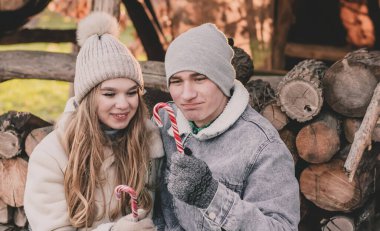 Yakacak odunların arkasında oturan ve ellerinde şeker tutan çift.