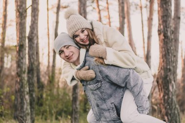 Kız adamın sırtına oturur ve bir çam ormanının arka planına gülümser.