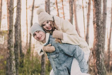 Kız adamın sırtına oturur ve bir çam ormanının arka planına gülümser.