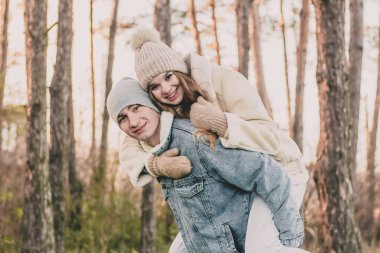 Kız adamın sırtına oturur ve bir çam ormanının arka planına gülümser.