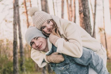 Kız adamın sırtına oturur ve bir çam ormanının arka planına gülümser.