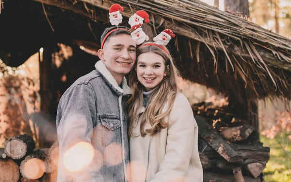 頭には新年の挨拶をしたカップルが 薪でできたガゼボの背景を見て笑っている — ストック写真