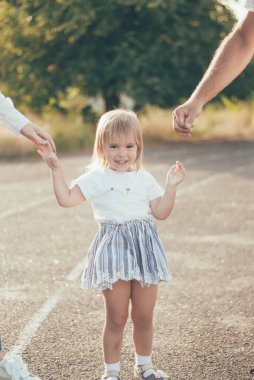Anne ve babanın elini tutan küçük kız.