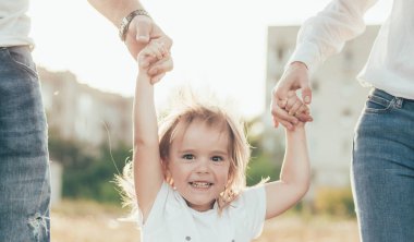 Anne ve baba kızlarıyla el ele tutuşuyorlar.