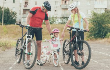 Annem ve babam küçük kızıma stadyumda bisiklet sürmeyi öğretiyorlar.