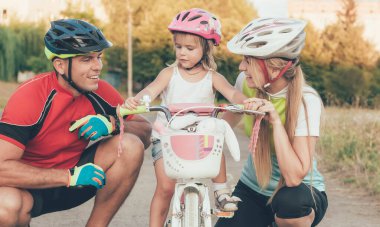 Annem ve babam küçük kızıma stadyumda bisiklet sürmeyi öğretiyorlar.