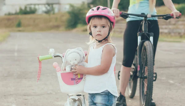 little daughter in a helmet ride bicycles with mom