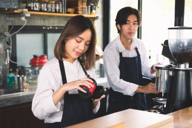 İki Asyalı garson kahve dükkanında bir fincan sıcak kahve yapıyor. Barista dükkanda kahve makinesiyle çalışıyor..