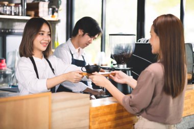 Bir müşteri baristaya sıcak latte sipariş ediyor. Asyalı Personel Kafe 'si sıcak kahve yapıp müşteriye servis yapıyor. Küçük işletme konsepti.