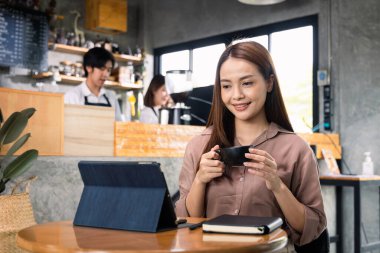 Tabletle çalışan genç ve güzel bir iş kadını kafeteryada oturuyor..