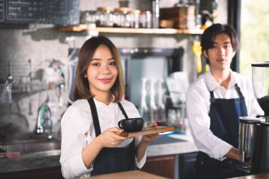 İki Asyalı garson kahve dükkanında bir fincan sıcak kahve yapıyor. Barista dükkanda kahve makinesiyle çalışıyor..