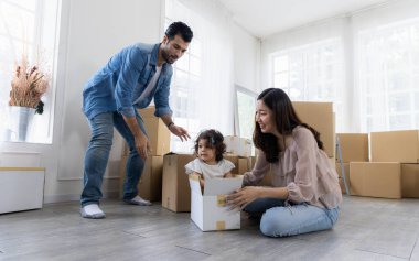 Kızı, bir karton kutuda oturup anne ve babasıyla oynuyor. Aile yeni bir eve taşındı. Ebeveynler ve çocuklar işleri birlikte organize ederken eğleniyorlar..