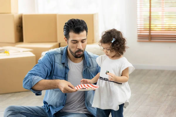 Happy moment family eating chocolate cookie in living room at home. Father and daughter laughing having a good meal in the morning.