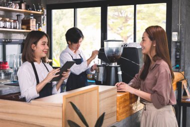 Bir müşteri baristaya sıcak latte sipariş ediyor. Asyalı Personel Kafe 'si sıcak kahve yapıp müşteriye servis yapıyor. Küçük işletme konsepti.
