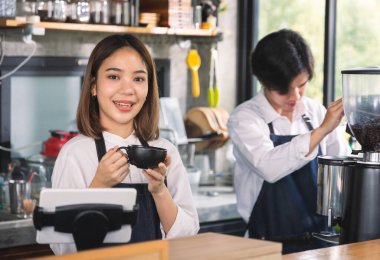 İki Asyalı garson kahve dükkanında bir fincan sıcak kahve yapıyor. Barista dükkanda kahve makinesiyle çalışıyor..