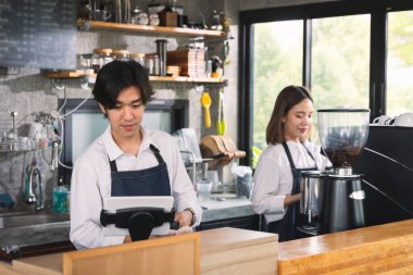 İki Asyalı garson kahve dükkanında bir fincan sıcak kahve yapıyor. Barista dükkanda kahve makinesiyle çalışıyor..