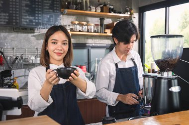 İki Asyalı garson kahve dükkanında bir fincan sıcak kahve yapıyor. Barista dükkanda kahve makinesiyle çalışıyor..