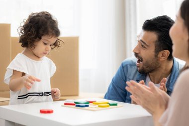 Ebeveynler ve kızları evdeki oturma odasında yerde oturan tahta bloklarla oynuyorlar. Aile yeni bir eve taşındı. Mutlu an. Çok ırklı baba, anne ve çocuk..