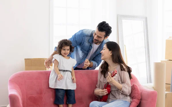 Happy family moment in the house. Father mother and daughter relaxing on red sofa. The family just moving in new house.