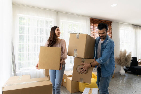 Семья только что купила новую мебель и помогла организовать дом. Муж и жена только что переехали. Они распаковывают посылку и расставляют ее на полу в гостиной..