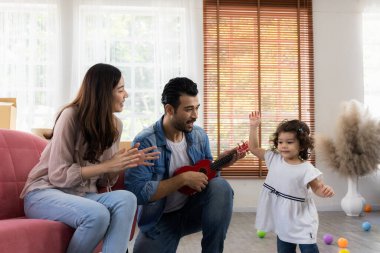Evde mutlu aile anları. Baba, anne ve kız kırmızı kanepede dinleniyorlar. Aile yeni eve taşınıyor..