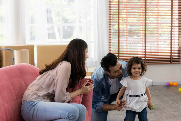 Happy family moment in the house. Father mother and daughter relaxing on red sofa. The family just moving in new house.