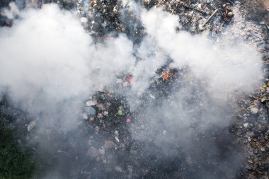 Çöp ve yangın atık sahasında yanıyor. Çöpleri, atıkları, çöpleri de arayın. Yanma, ısı ve alevle yıkım. Oklar duman, hava kirliliğinin zehirli nedeni, çevresel hasar ve küresel ısınma.