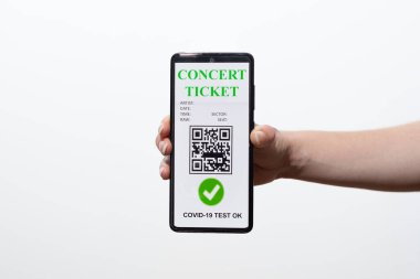 Aşılanmış kişi covid-19 salgını sırasında konser biletini göstermek için cep telefonundaki dijital sağlık pasaport uygulamasını kullanıyor