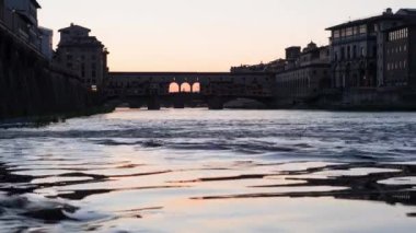 Floransa 'daki Ponte Vecchio' da gün batımında Arno nehri, Toskana, İtalya 'nın sularında ışık yansımaları görülüyor.