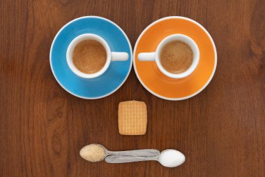 Kurabiyeli kahve fincanları ve tahta arka planda kaşıklar.