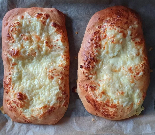 Pişirme kağıdının arka planında ev yapımı peynirli khachapuri. Gürcistan mutfağı. Yiyecek konsepti