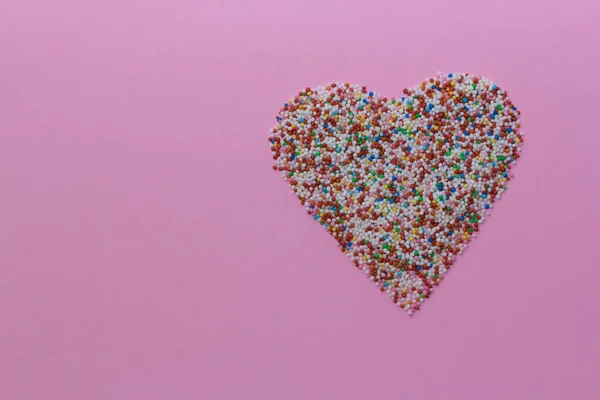 Saupoudrer disposées en forme de coeur sur un fond rustique rose. Saint Valentin, carte de voeux. Arroseurs pour confiseries et pâtisseries. Espace de copie, vue du dessus — Photo