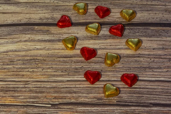 Coeurs chocolatés en feuille d'or et rouge sur fond de bois brun. Saint Valentin, carte de voeux. Espace de copie, vue de dessus, concept d'amour — Photo