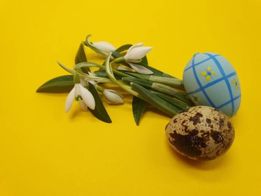 Sarı arka planda renkli Paskalya yumurtaları ve bahar çiçekleri. Paskalya tebriği, kartpostal, kopyalama alanı, paskalya süslemeleri