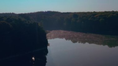 Güneşin doğuşundaki güzel göl. Ormanla çevrili bir göl ve ılık sabah ışığı..