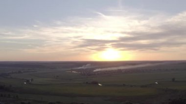 Tarlada yanan çimenler. Yangının başlangıcı. Gün batımında duman içinde bir tarla