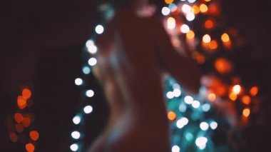 Kız ya da genç bir kadın bir Noel ağacını çelenkle süslüyor.