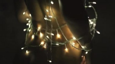 Kız ya da genç bir kadın bir Noel ağacını çelenkle süslüyor.