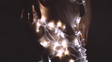 Kız ya da genç bir kadın bir Noel ağacını çelenkle süslüyor.