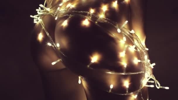 Fille ou jeune femme décore un arbre de Noël avec une guirlande décorations — Video