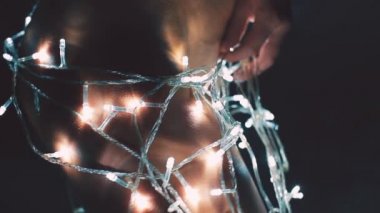 Kız ya da genç bir kadın bir Noel ağacını çelenkle süslüyor.