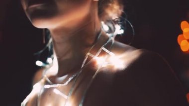 Kız ya da genç bir kadın bir Noel ağacını çelenkle süslüyor.