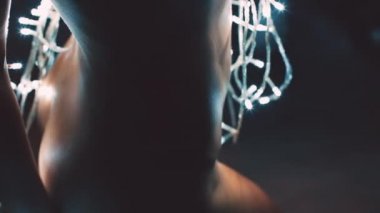 Kız ya da genç bir kadın bir Noel ağacını çelenkle süslüyor.