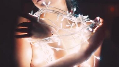 Kız ya da genç bir kadın bir Noel ağacını çelenkle süslüyor.