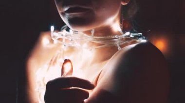 Kız ya da genç bir kadın bir Noel ağacını çelenkle süslüyor.